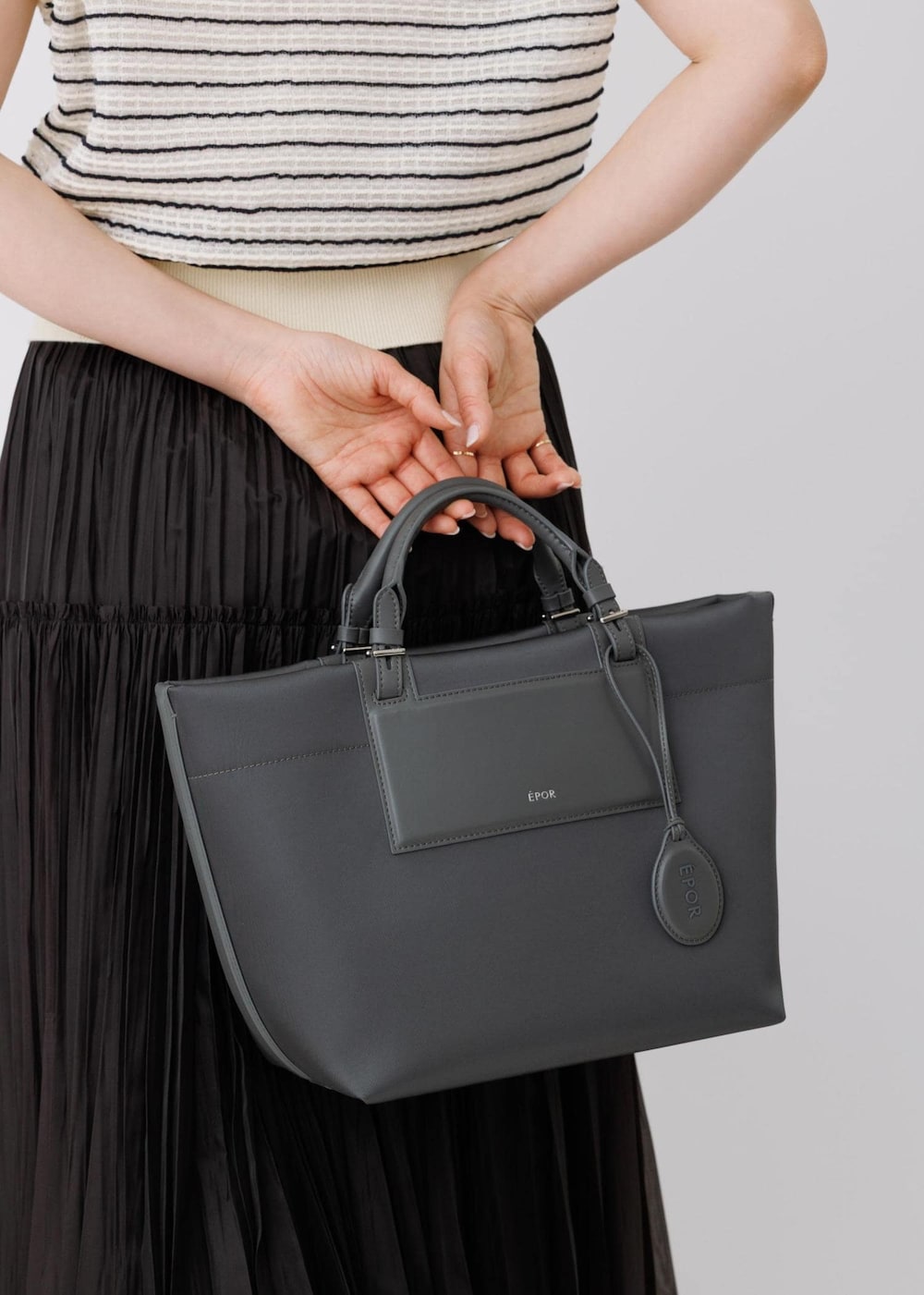 ブラック系のスカート、ホワイト系のニット/セーター、グレー系のトートバッグを着用したレディースの春コーディネートの7枚目の写真