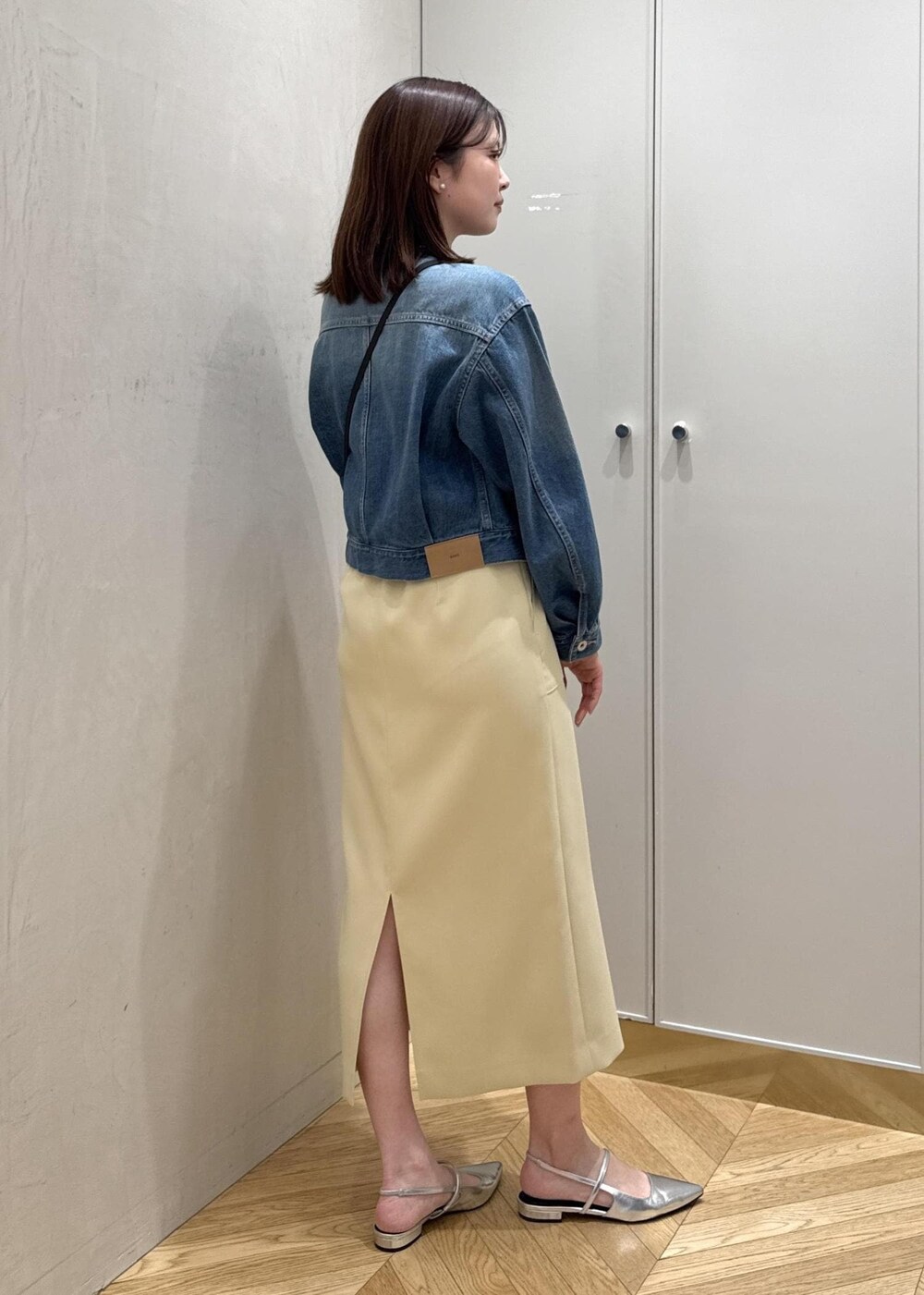 ベージュ系のショルダーバッグ、イエロー系のスカート、ブルー系のデニムジャケットを着用したレディースの春コーディネートの3枚目の写真