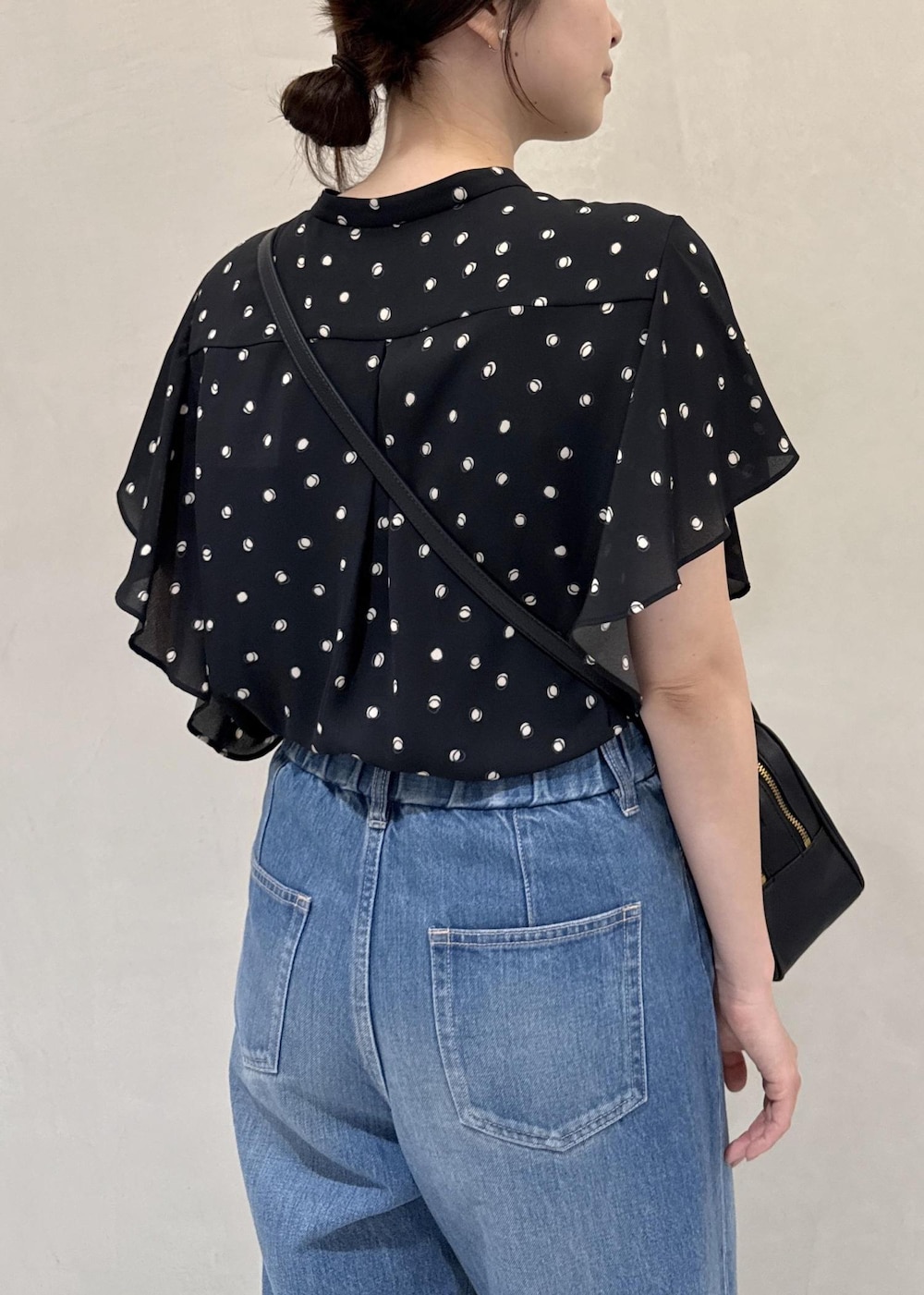 ブルー系のデニムパンツ、ブラック系のシャツ/ブラウス、ブラック系のハンドバッグを着用したレディースの夏コーディネートの6枚目の写真