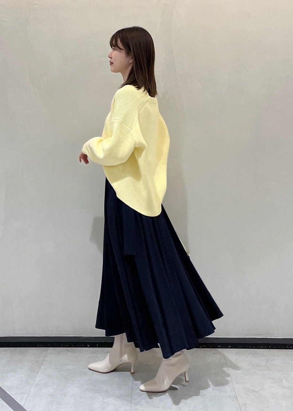 ホワイト系のハンドバッグ、ホワイト系のブーツ、ブルー系のスカートを着用したレディースの冬コーディネートの2枚目の写真