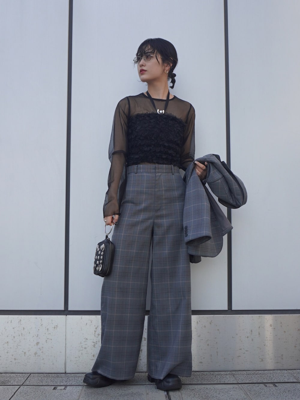 ブラック系のチューブトップ、ブラック系のトップス、グレー系のスラックスを着用したレディースの春コーディネートの3枚目の写真