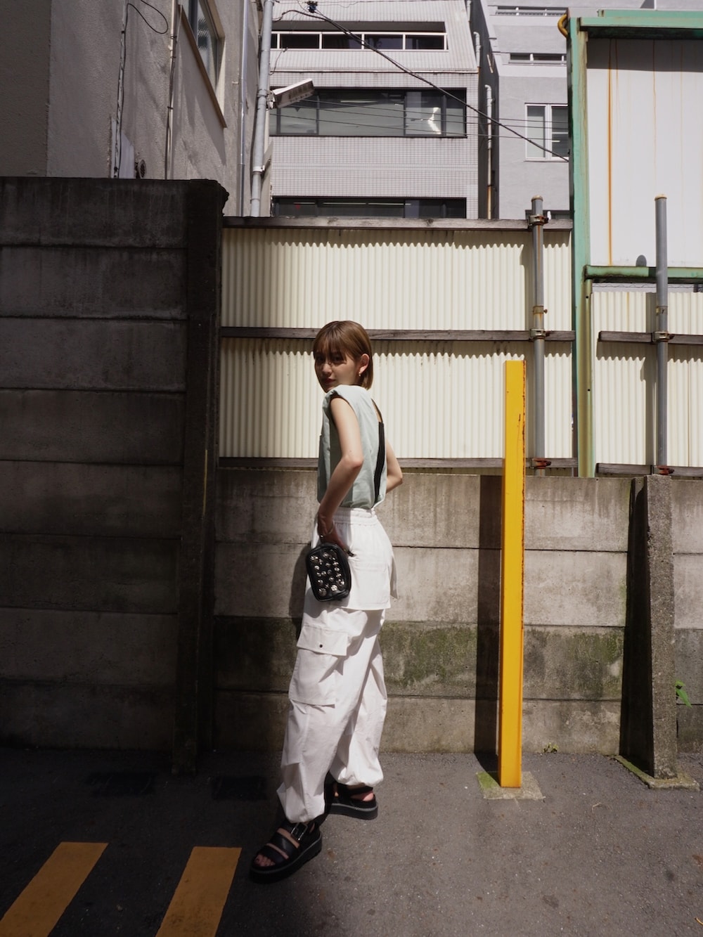 グリーン系のタンクトップ、ホワイト系のカーゴパンツを着用したレディースの夏コーディネートの2枚目の写真