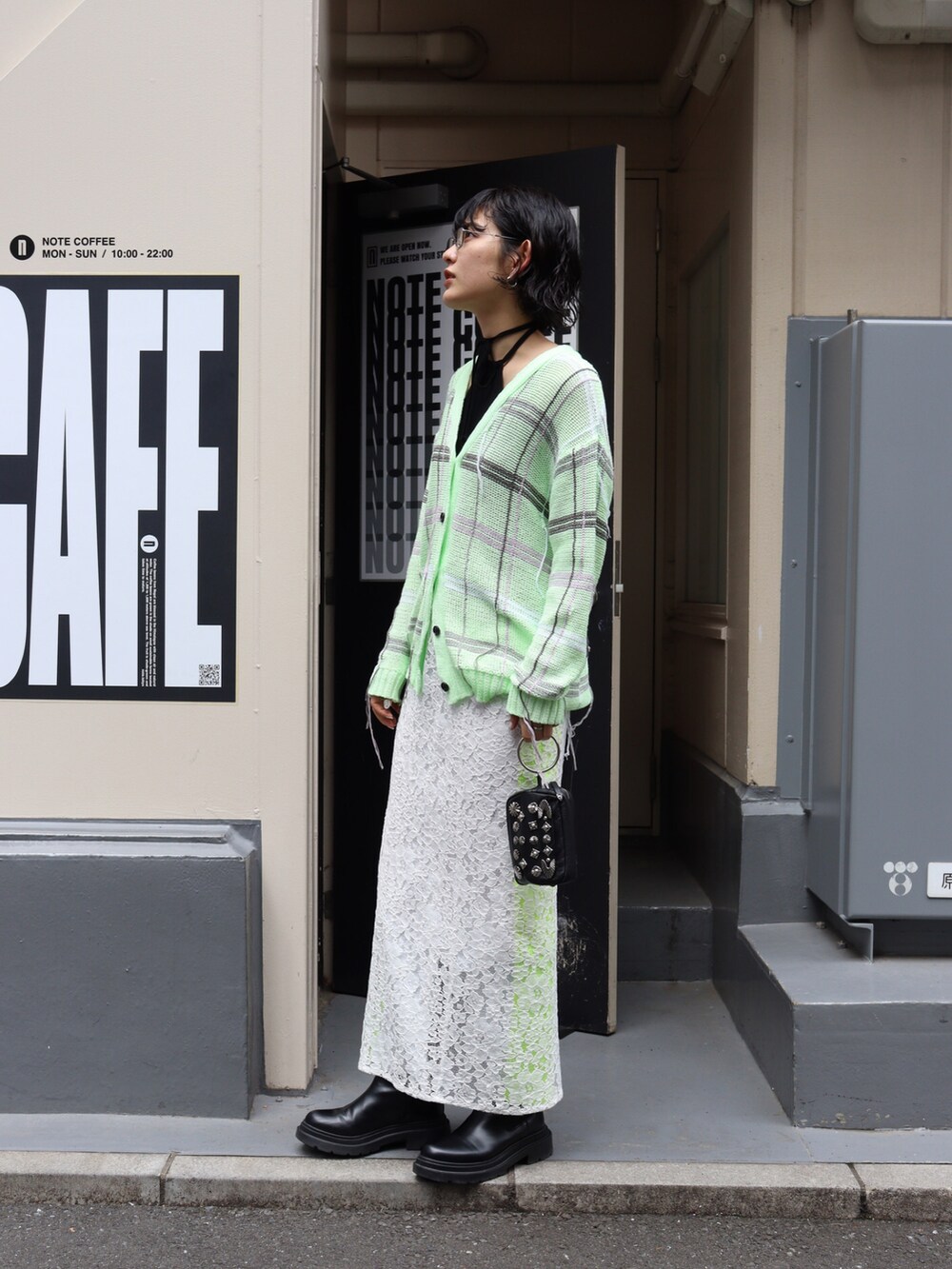 グリーン系のカーディガン/ボレロ、ホワイト系のスカート、ブラック系のTシャツ/カットソーを着用したレディースの春コーディネートの2枚目の写真