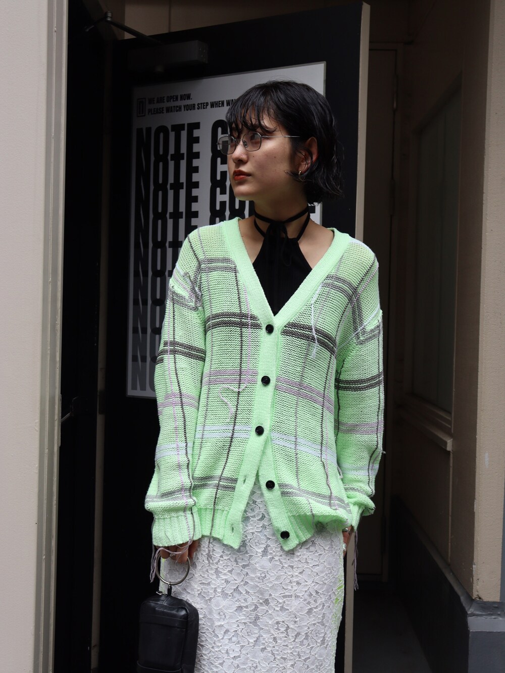 グリーン系のカーディガン/ボレロ、ホワイト系のスカート、ブラック系のTシャツ/カットソーを着用したレディースの春コーディネートの3枚目の写真