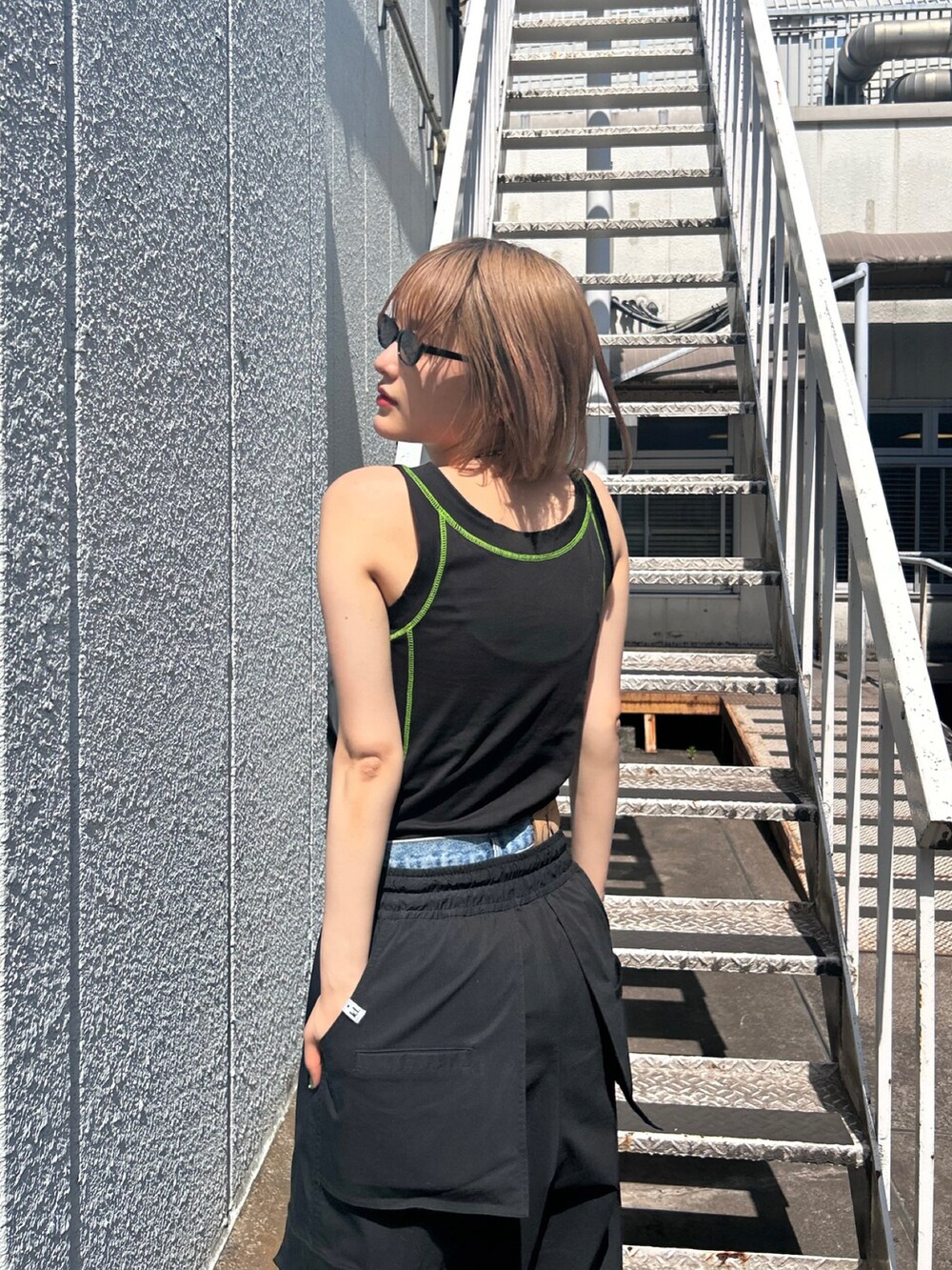 ブラック系のタンクトップ、ブラック系のカーゴパンツ、ブラック系のシューズを着用したレディースの春コーディネートの2枚目の写真