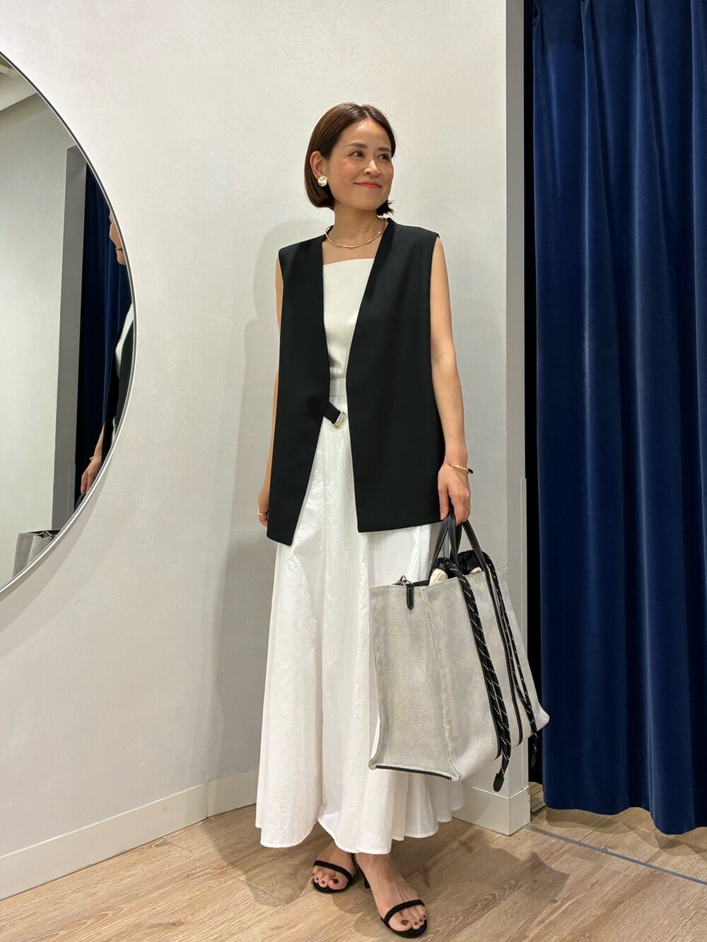 ブラック系のベスト、ホワイト系のキャミソール、ホワイト系のスカートを着用したレディースの夏コーディネートの4枚目の写真