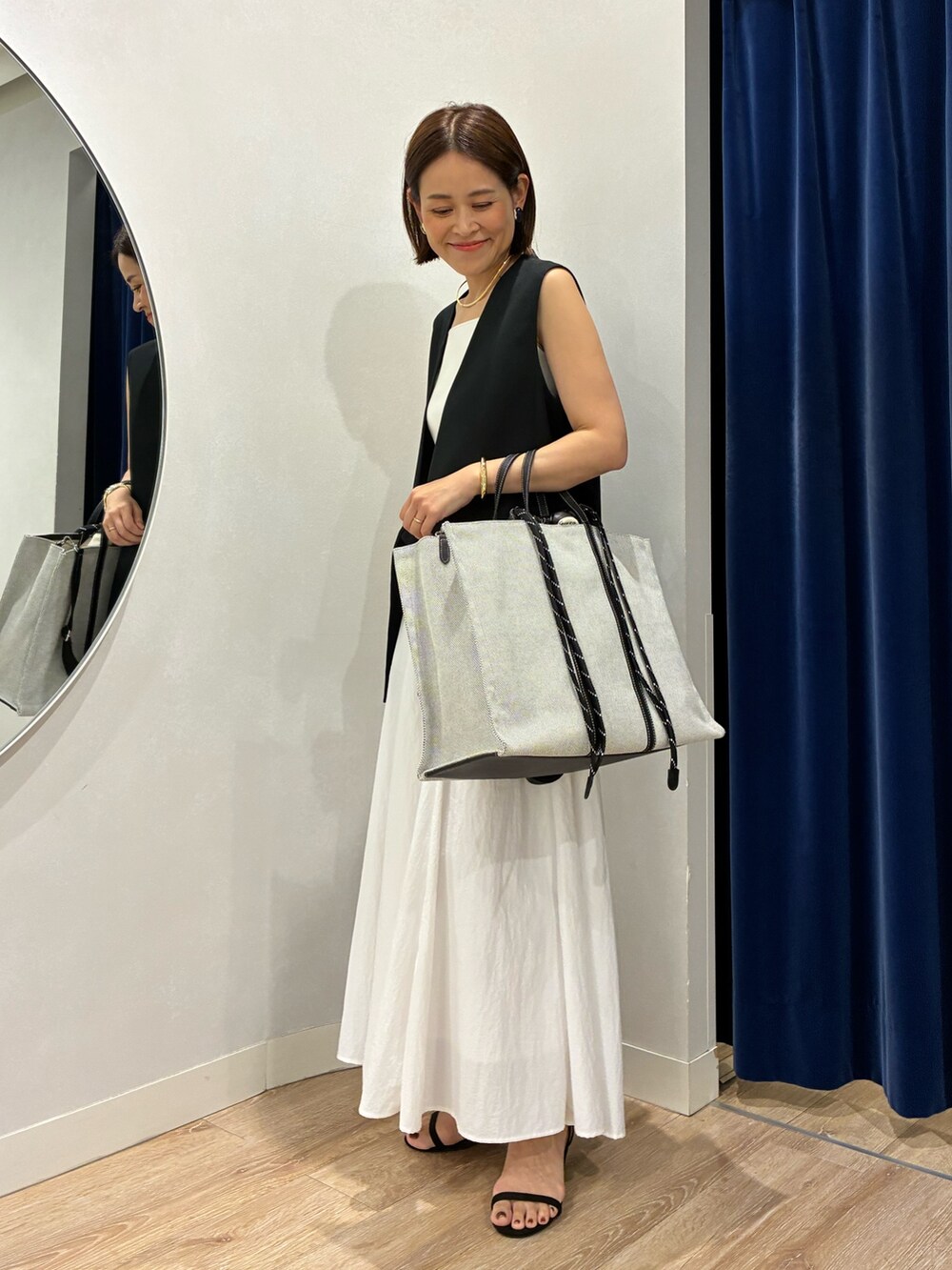 ブラック系のベスト、ホワイト系のキャミソール、ホワイト系のスカートを着用したレディースの夏コーディネートの7枚目の写真