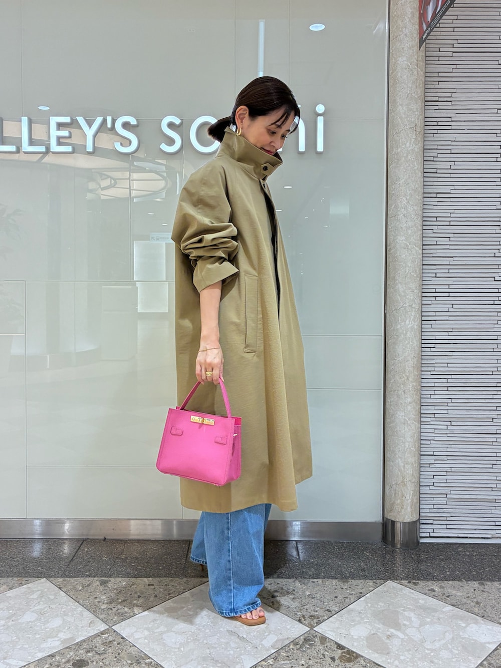 ベージュ系のダッフルコート、ピンク系のショルダーバッグ、ブルー系のデニムパンツを着用したレディースの秋コーディネートの4枚目の写真