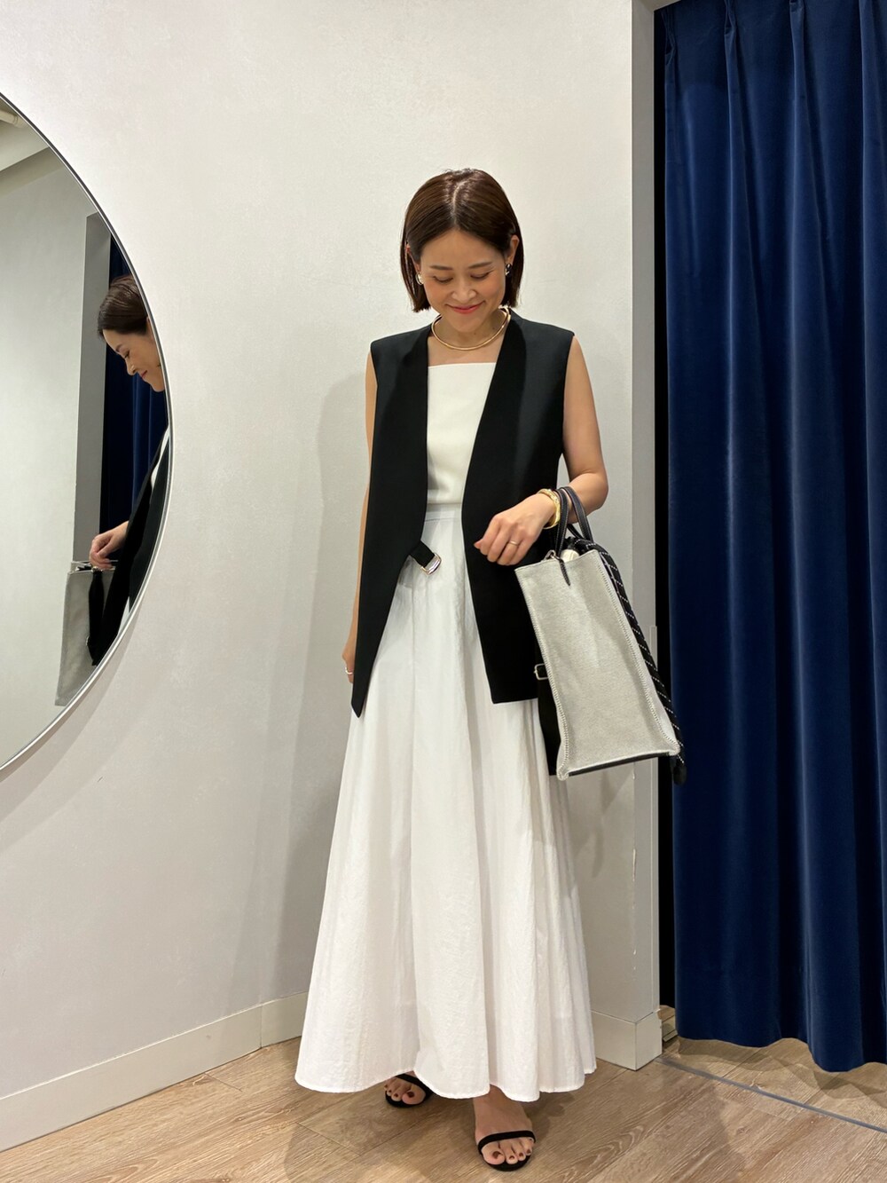 ブラック系のベスト、ホワイト系のキャミソール、ホワイト系のスカートを着用したレディースの夏コーディネートの8枚目の写真
