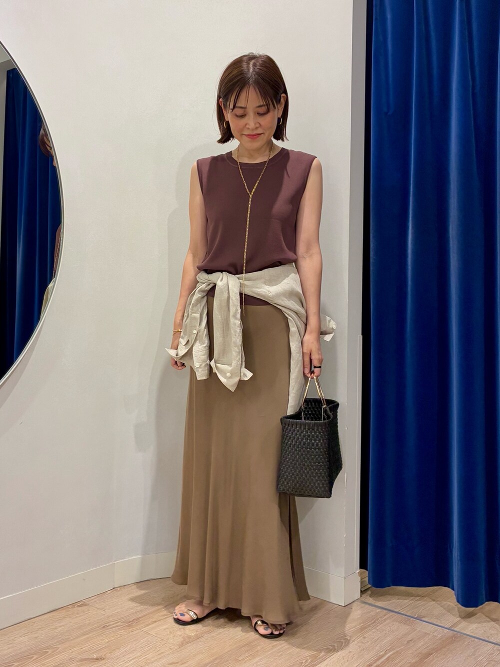 ブラウン系のニット/セーター、ベージュ系のシャツ/ブラウス、ブラック系のかごバッグを着用したレディースの夏コーディネートの5枚目の写真