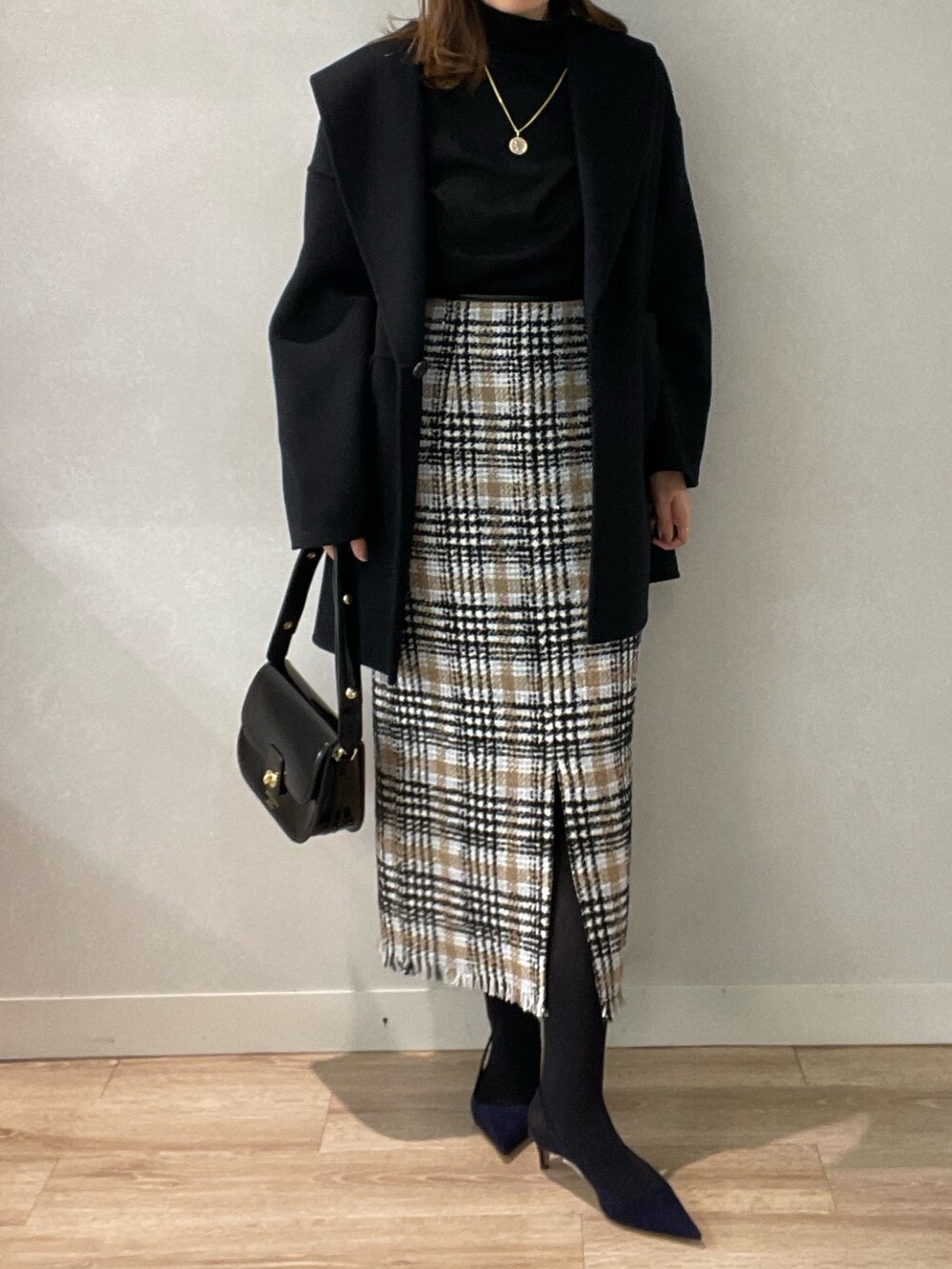 ブラック系のスカート、ブラック系のショルダーバッグ、ブラック系のニット/セーターを着用したレディースの秋コーディネートの7枚目の写真