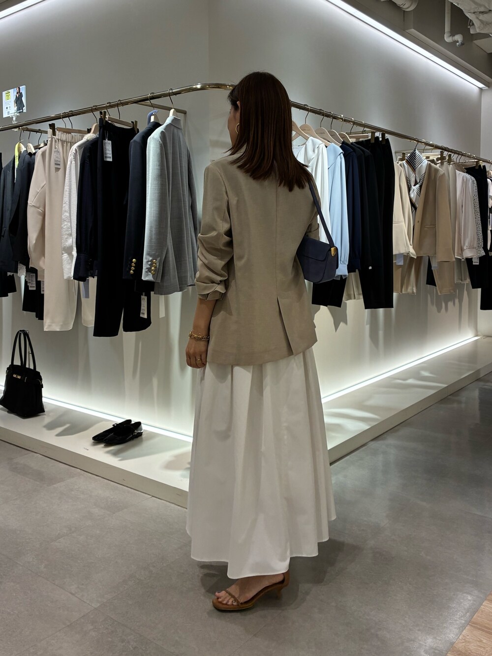 ベージュ系のテーラードジャケット、ホワイト系のスカート、ブラウン系のニット/セーターを着用したレディースの春コーディネートの4枚目の写真