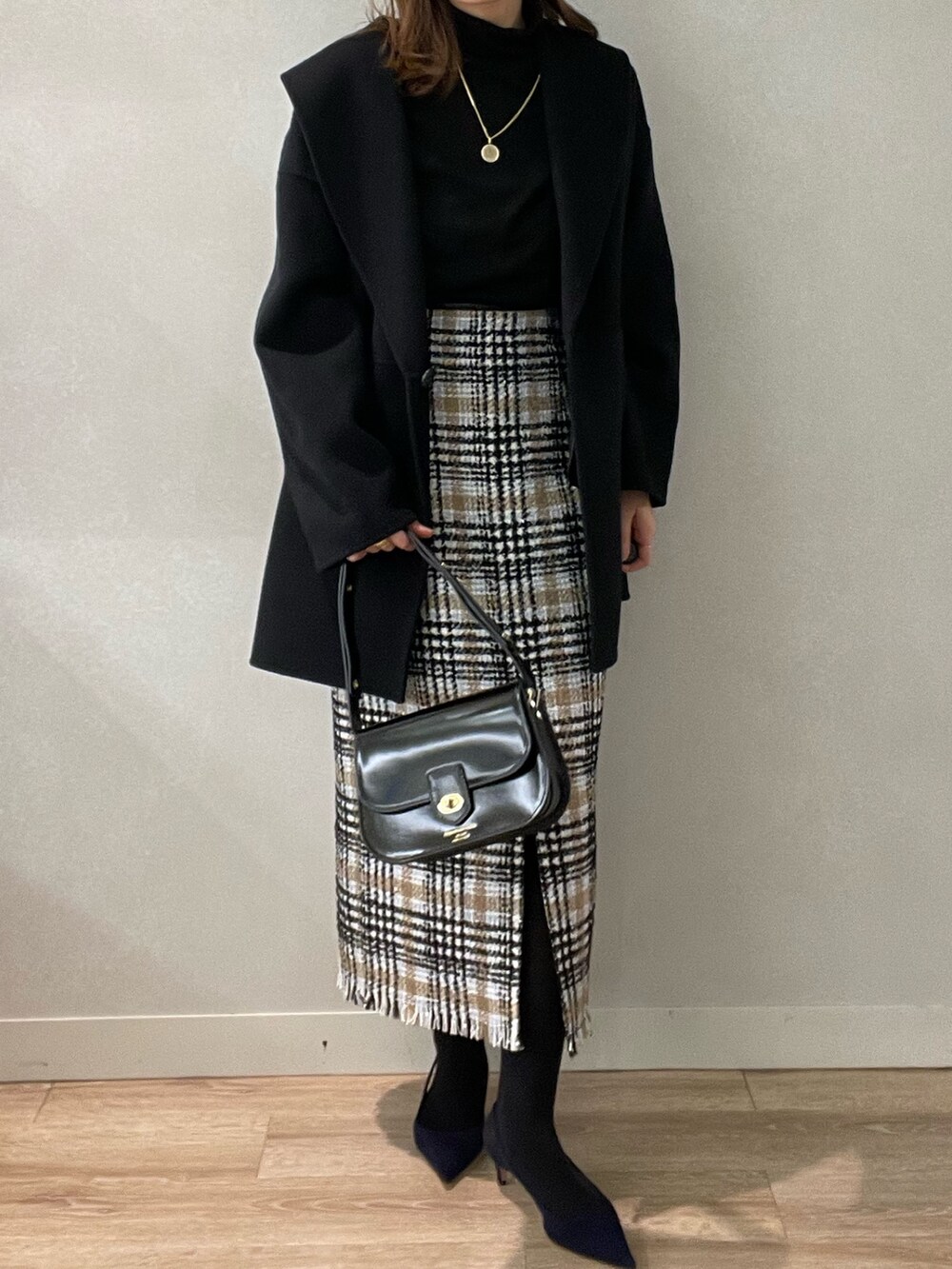 ブラック系のスカート、ブラック系のショルダーバッグ、ブラック系のニット/セーターを着用したレディースの秋コーディネートの9枚目の写真