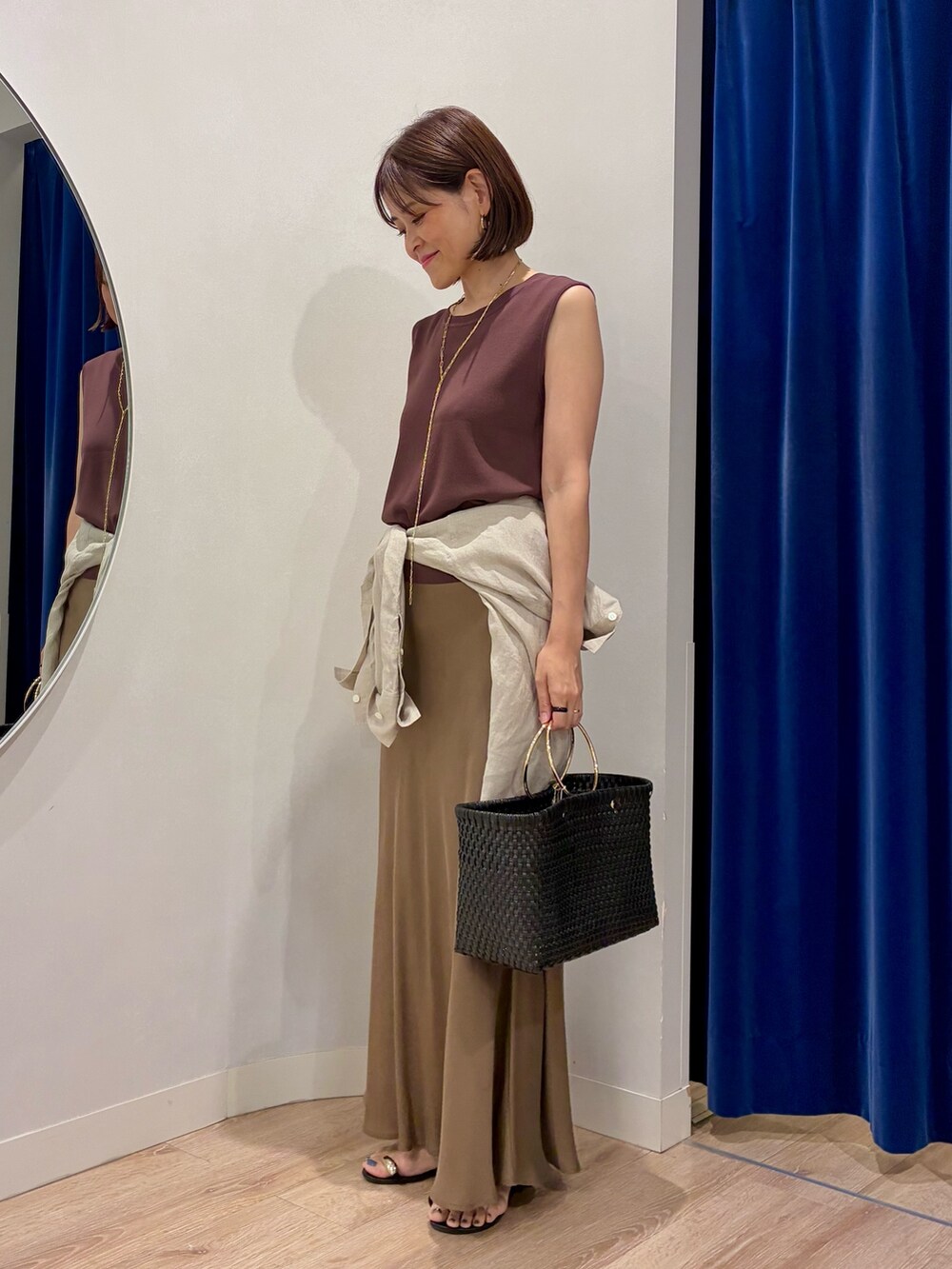 ブラウン系のニット/セーター、ベージュ系のシャツ/ブラウス、ブラック系のかごバッグを着用したレディースの夏コーディネートの2枚目の写真