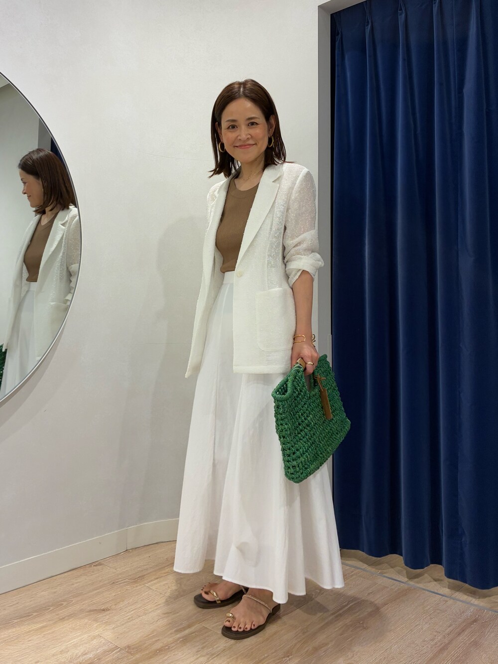 ブラウン系のタンクトップ、ホワイト系のテーラードジャケット、ホワイト系のスカートを着用したレディースの春コーディネートの2枚目の写真