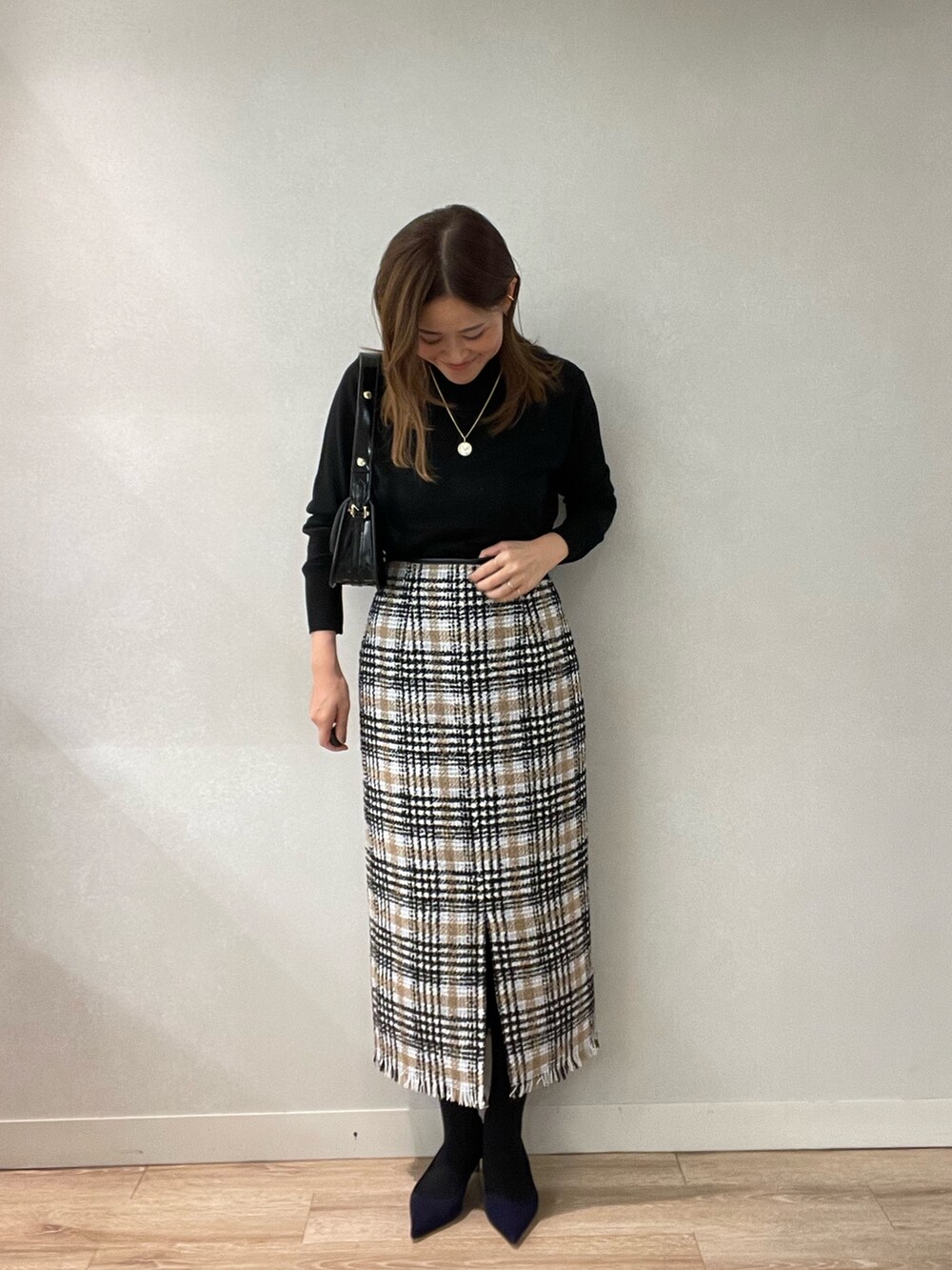 ブラック系のスカート、ブラック系のショルダーバッグ、ブラック系のニット/セーターを着用したレディースの秋コーディネートの2枚目の写真