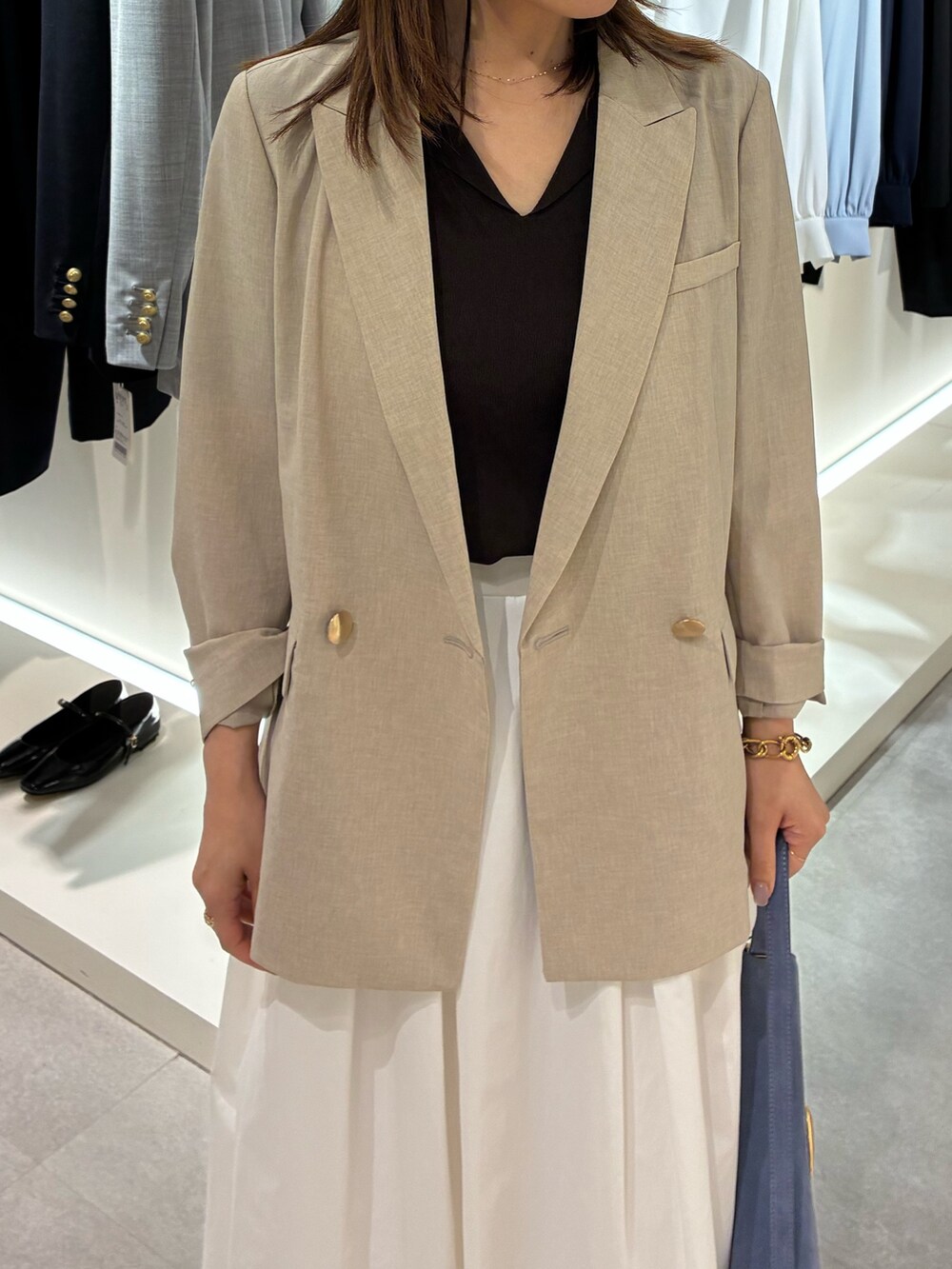 ベージュ系のテーラードジャケット、ホワイト系のスカート、ブラウン系のニット/セーターを着用したレディースの春コーディネートの3枚目の写真