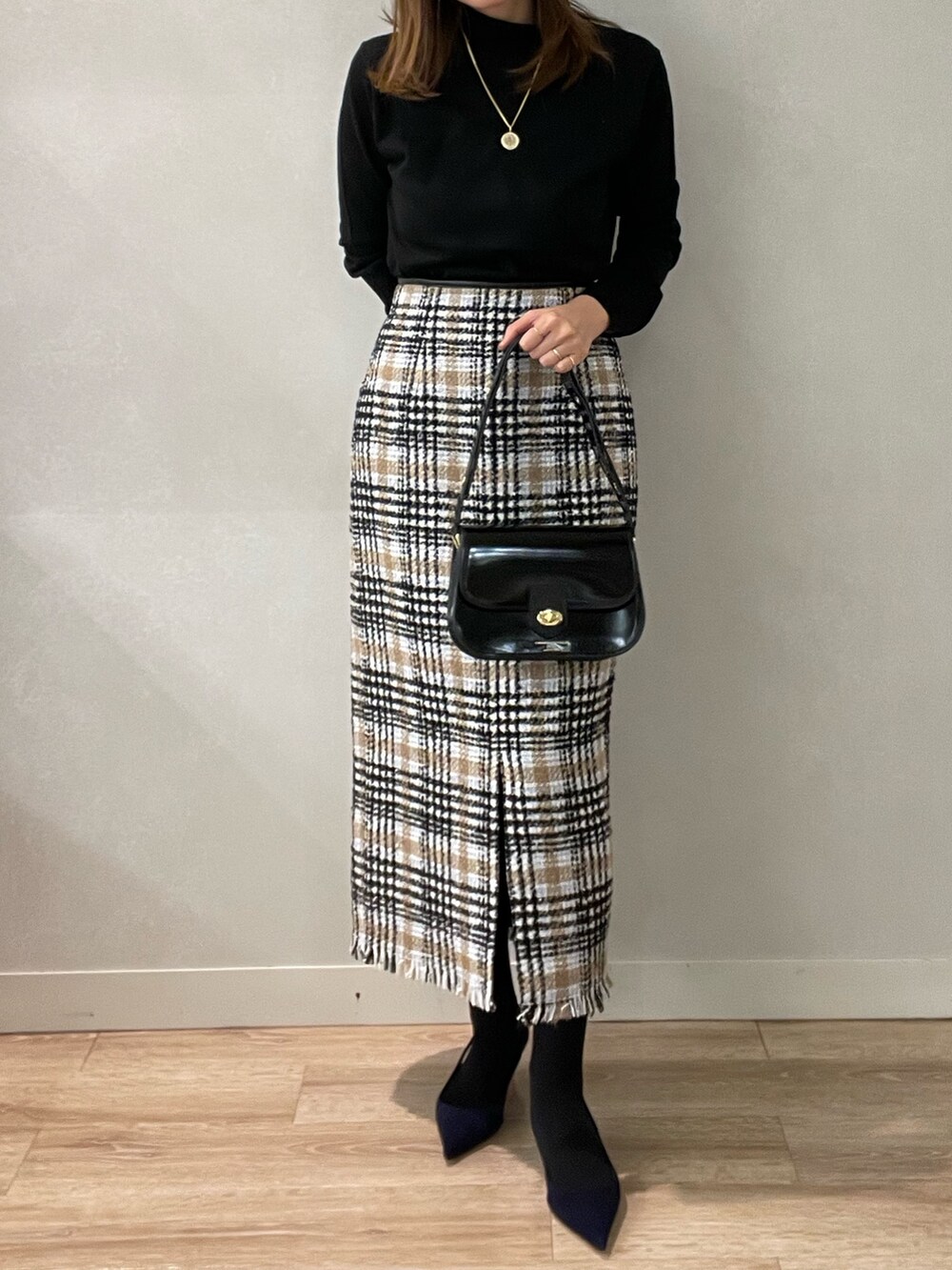 ブラック系のスカート、ブラック系のショルダーバッグ、ブラック系のニット/セーターを着用したレディースの秋コーディネートの3枚目の写真