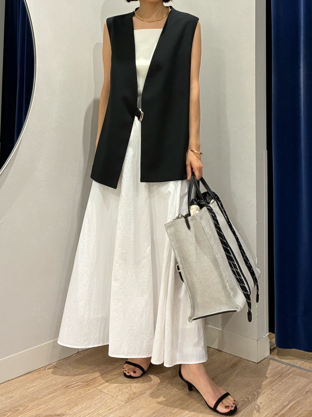 ブラック系のベスト、ホワイト系のキャミソール、ホワイト系のスカートを着用したレディースの夏コーディネートの3枚目の写真