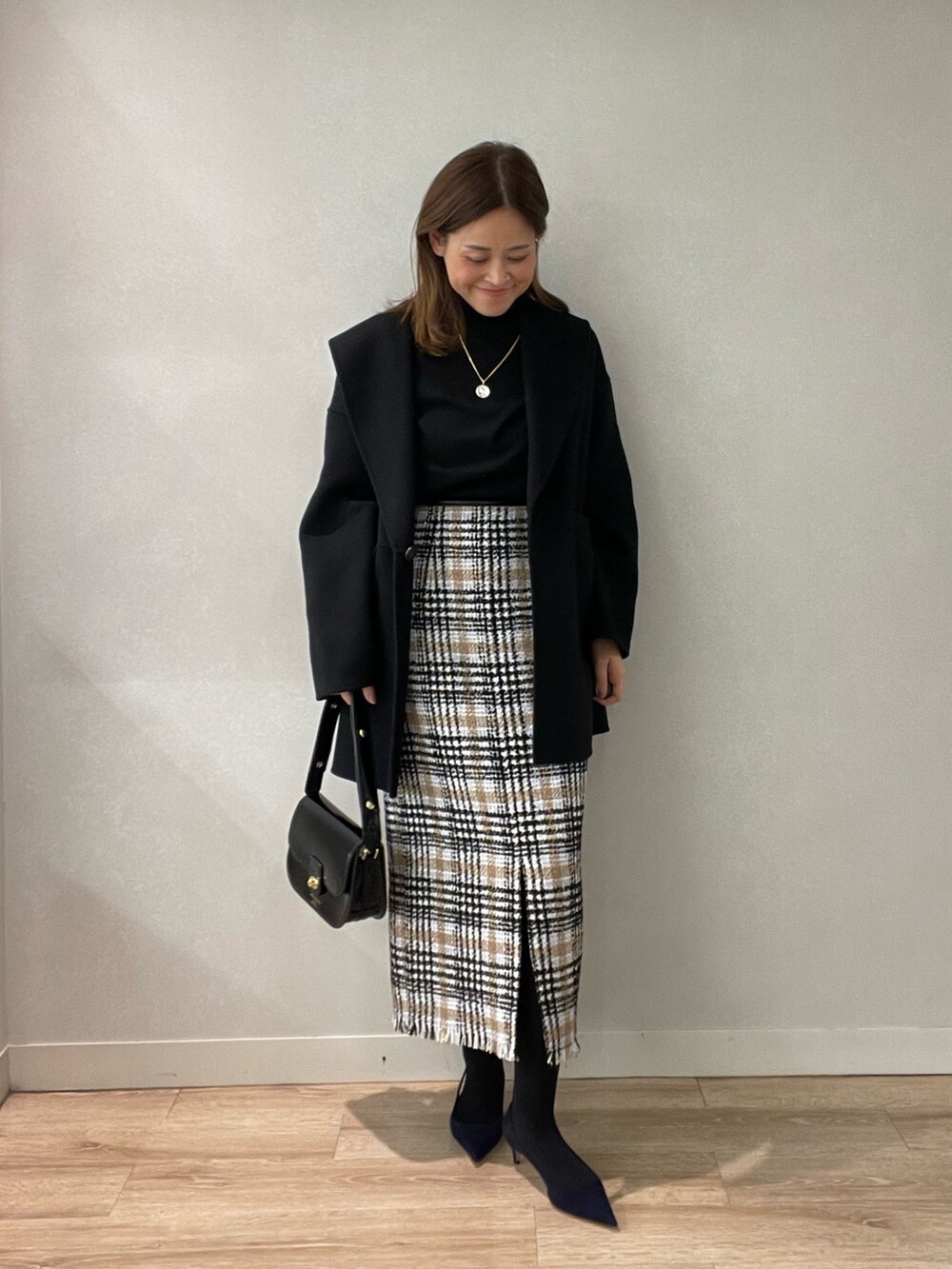 ブラック系のスカート、ブラック系のショルダーバッグ、ブラック系のニット/セーターを着用したレディースの秋コーディネートの8枚目の写真