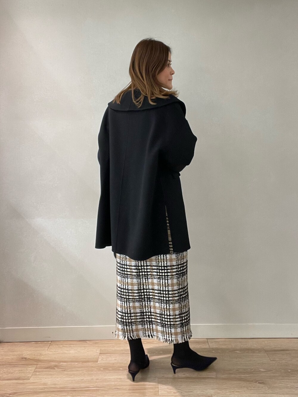 ブラック系のスカート、ブラック系のショルダーバッグ、ブラック系のニット/セーターを着用したレディースの秋コーディネートの6枚目の写真