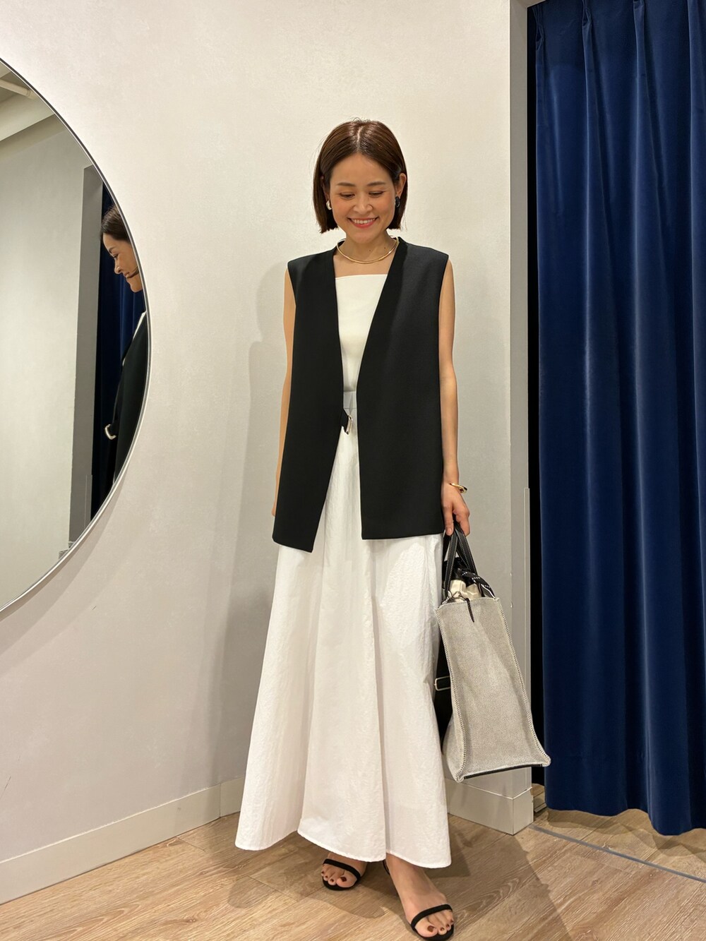 ブラック系のベスト、ホワイト系のキャミソール、ホワイト系のスカートを着用したレディースの夏コーディネートの2枚目の写真