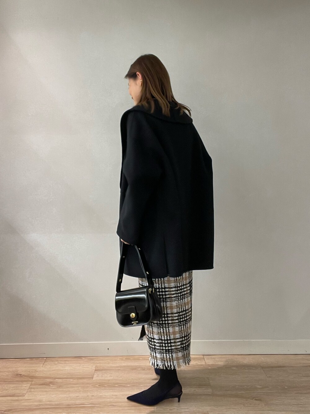 ブラック系のスカート、ブラック系のショルダーバッグ、ブラック系のニット/セーターを着用したレディースの秋コーディネートの5枚目の写真