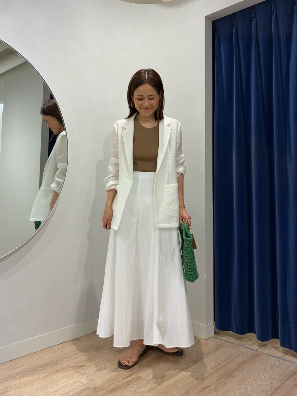 ブラウン系のタンクトップ、ホワイト系のテーラードジャケット、ホワイト系のスカートを着用したレディースの春コーディネートの3枚目の写真