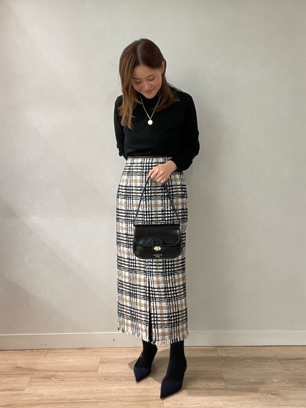 ブラック系のスカート、ブラック系のショルダーバッグ、ブラック系のニット/セーターを着用したレディースの秋コーディネートの4枚目の写真