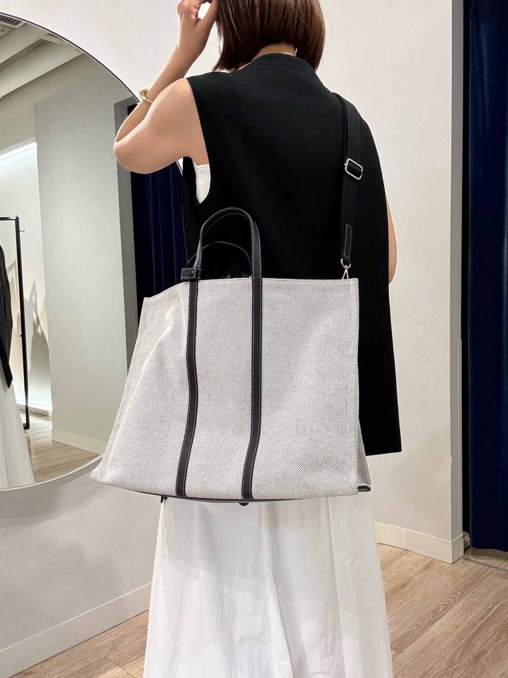 ブラック系のベスト、ホワイト系のキャミソール、ホワイト系のスカートを着用したレディースの夏コーディネートの10枚目の写真