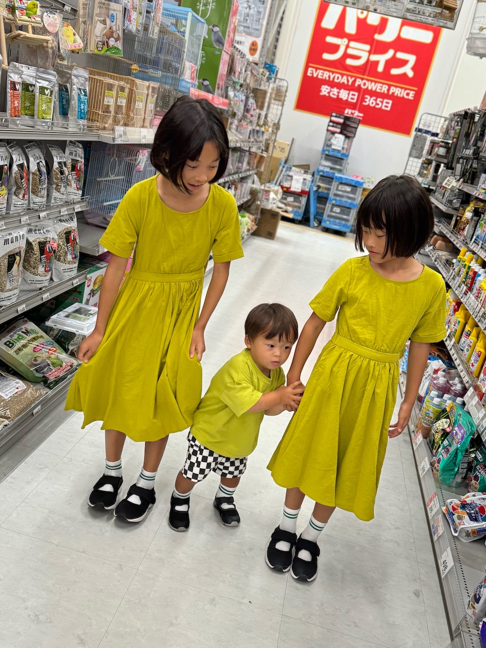 イエロー系のワンピース、ブラック系のサンダル、ブラック系のカーゴパンツを着用したキッズの夏コーディネートの2枚目の写真