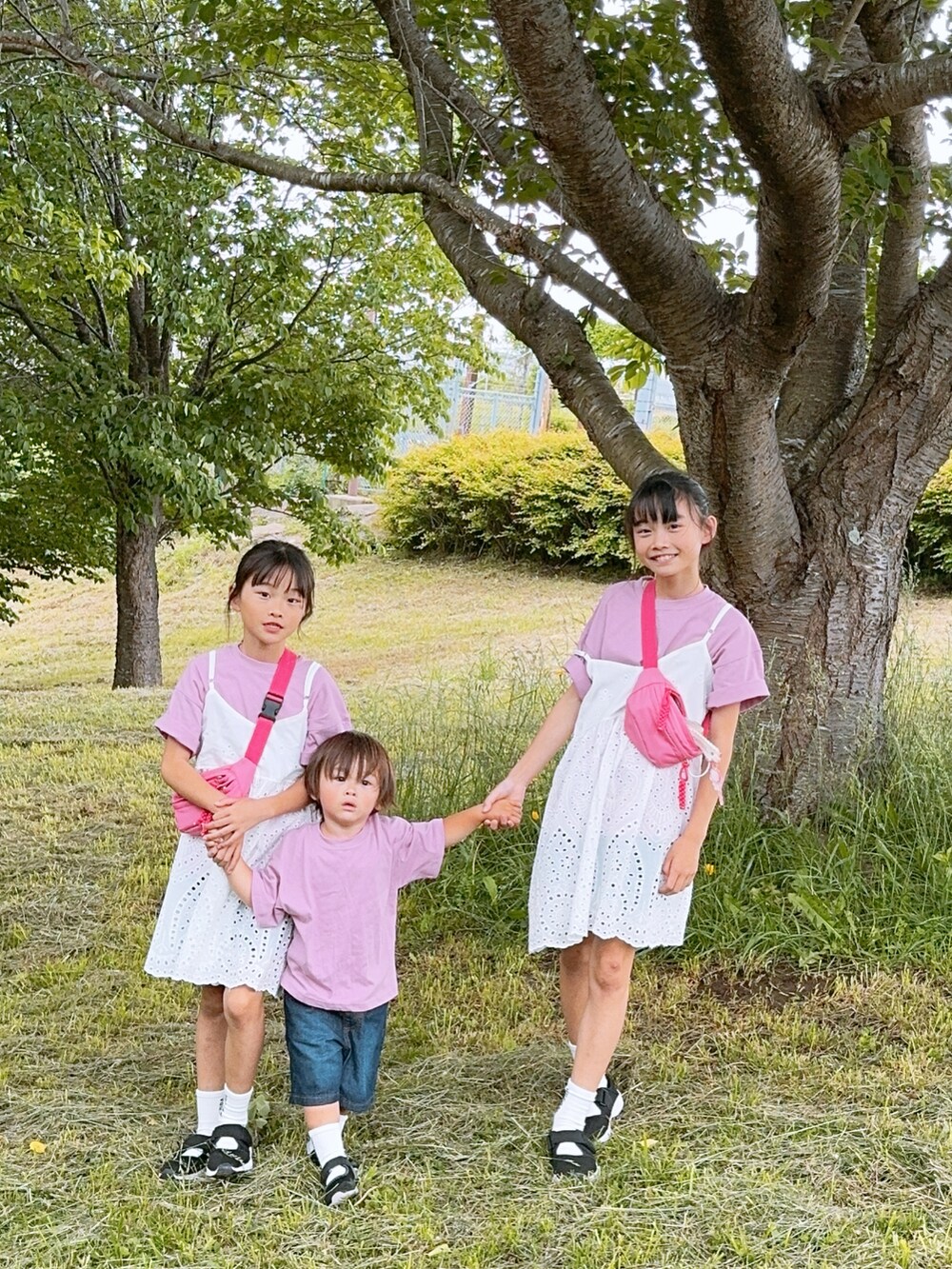 ホワイト系のワンピース、ブラック系のサンダル、ブルー系のデニムパンツを着用したキッズの春コーディネートの2枚目の写真