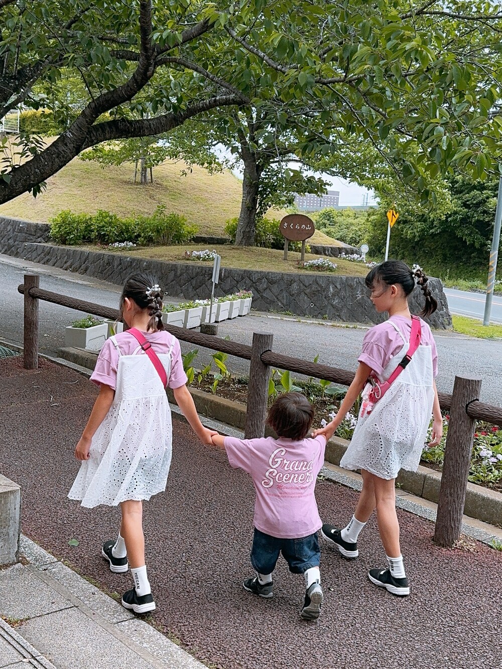 ホワイト系のワンピース、ブラック系のサンダル、ブルー系のデニムパンツを着用したキッズの春コーディネートの3枚目の写真