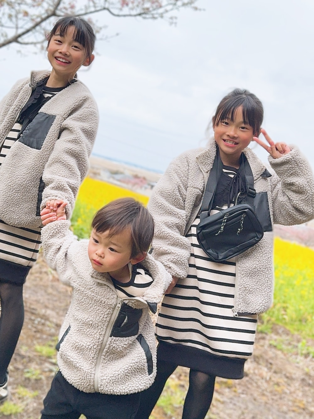 グレー系のブルゾン、ベージュ系のワンピース、ブラック系のスニーカーを着用したキッズの春コーディネートの2枚目の写真