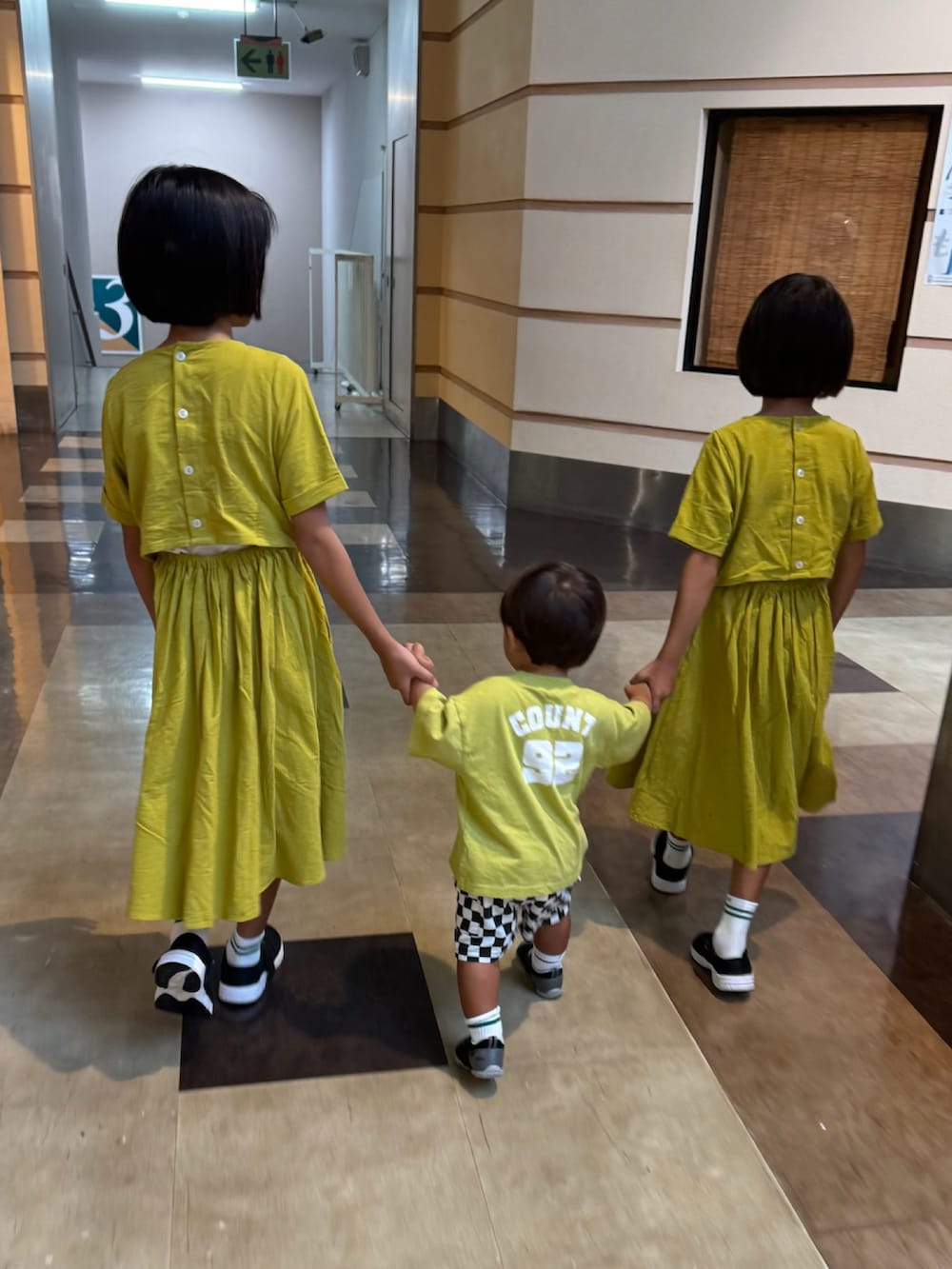 イエロー系のワンピース、ブラック系のサンダル、ブラック系のカーゴパンツを着用したキッズの夏コーディネートの3枚目の写真