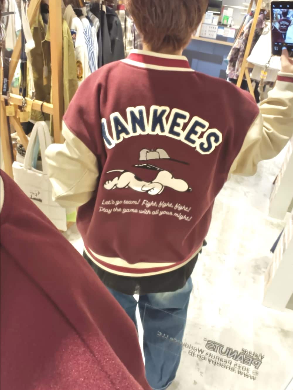 レッド系のスタジャン、ブルー系のデニムパンツ、ホワイト系のシャツ/ブラウスを着用したレディースの秋コーディネートの2枚目の写真