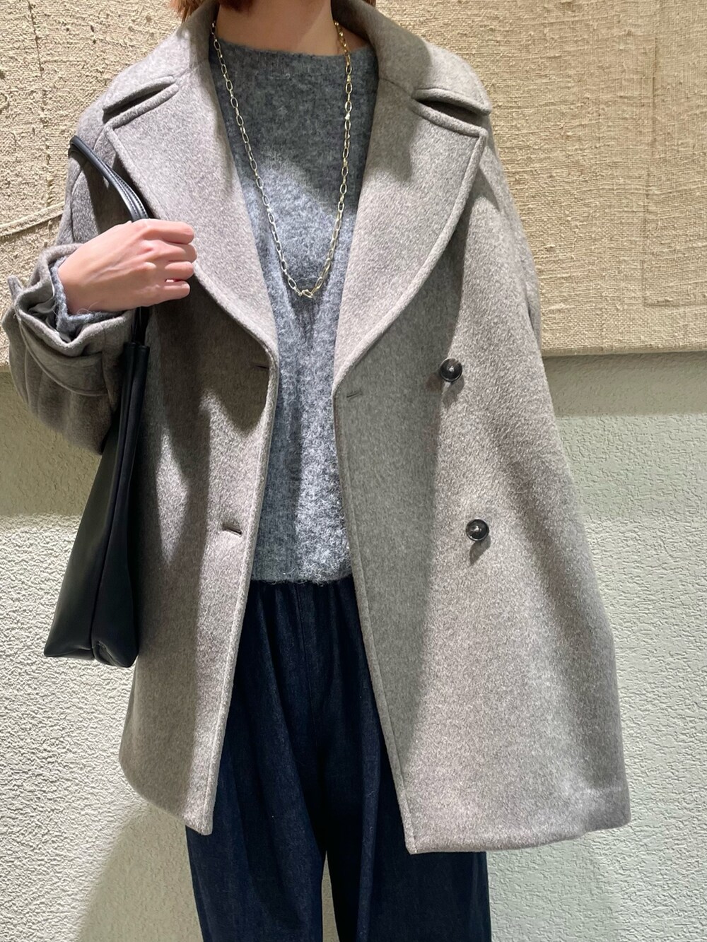 グレー系のニット/セーター、グレー系のピーコート、ブルー系のデニムパンツを着用したレディースの冬コーディネートの2枚目の写真