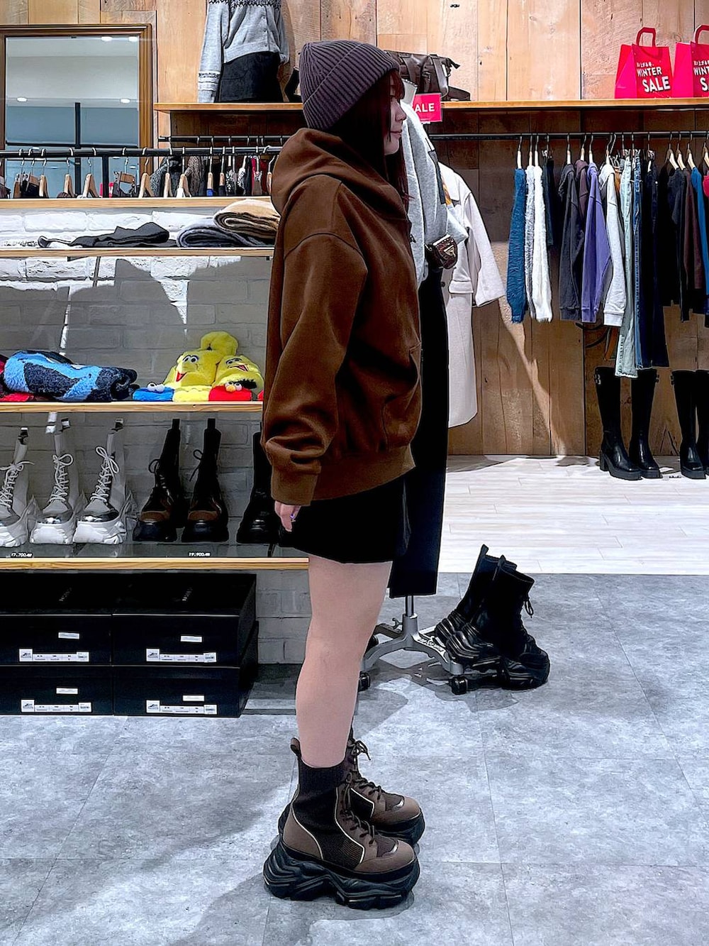 ブラウン系のブーツ、ブラック系のスカート、ブラウン系のパーカーを着用したレディースの冬コーディネートの3枚目の写真