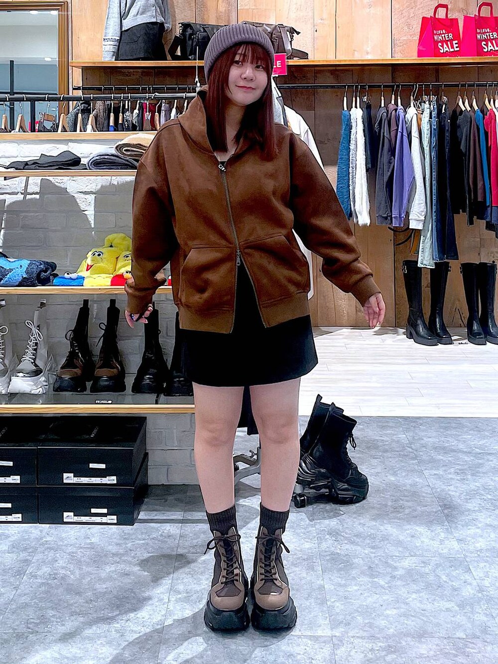 ブラウン系のブーツ、ブラック系のスカート、ブラウン系のパーカーを着用したレディースの冬コーディネートの6枚目の写真