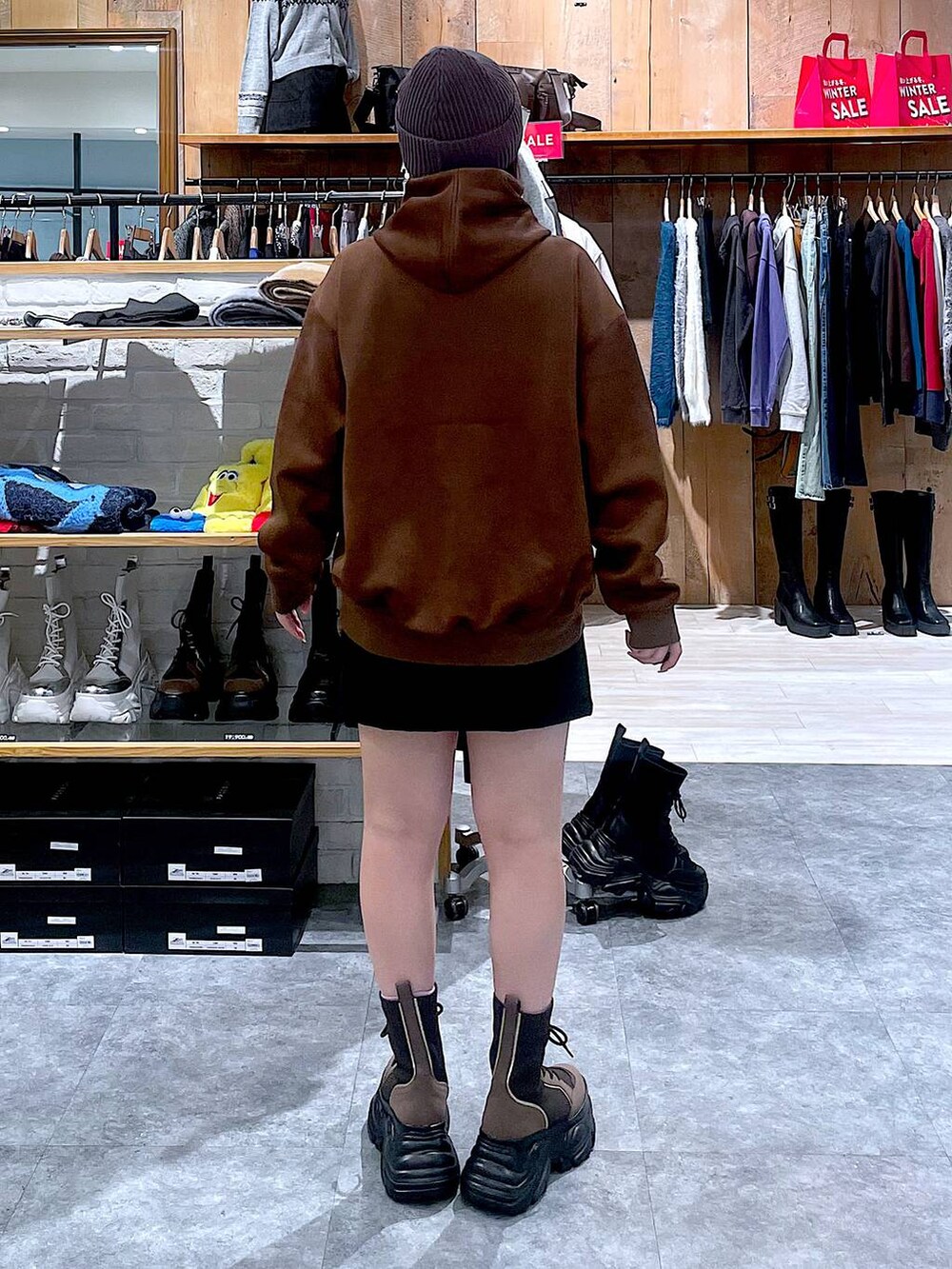 ブラウン系のブーツ、ブラック系のスカート、ブラウン系のパーカーを着用したレディースの冬コーディネートの5枚目の写真