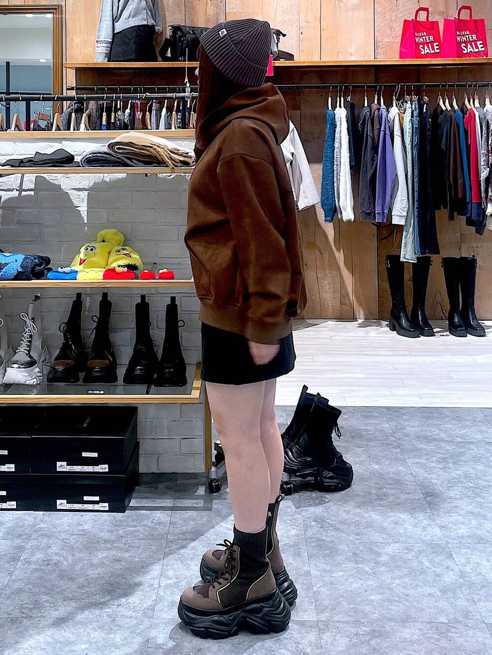 ブラウン系のブーツ、ブラック系のスカート、ブラウン系のパーカーを着用したレディースの冬コーディネートの4枚目の写真