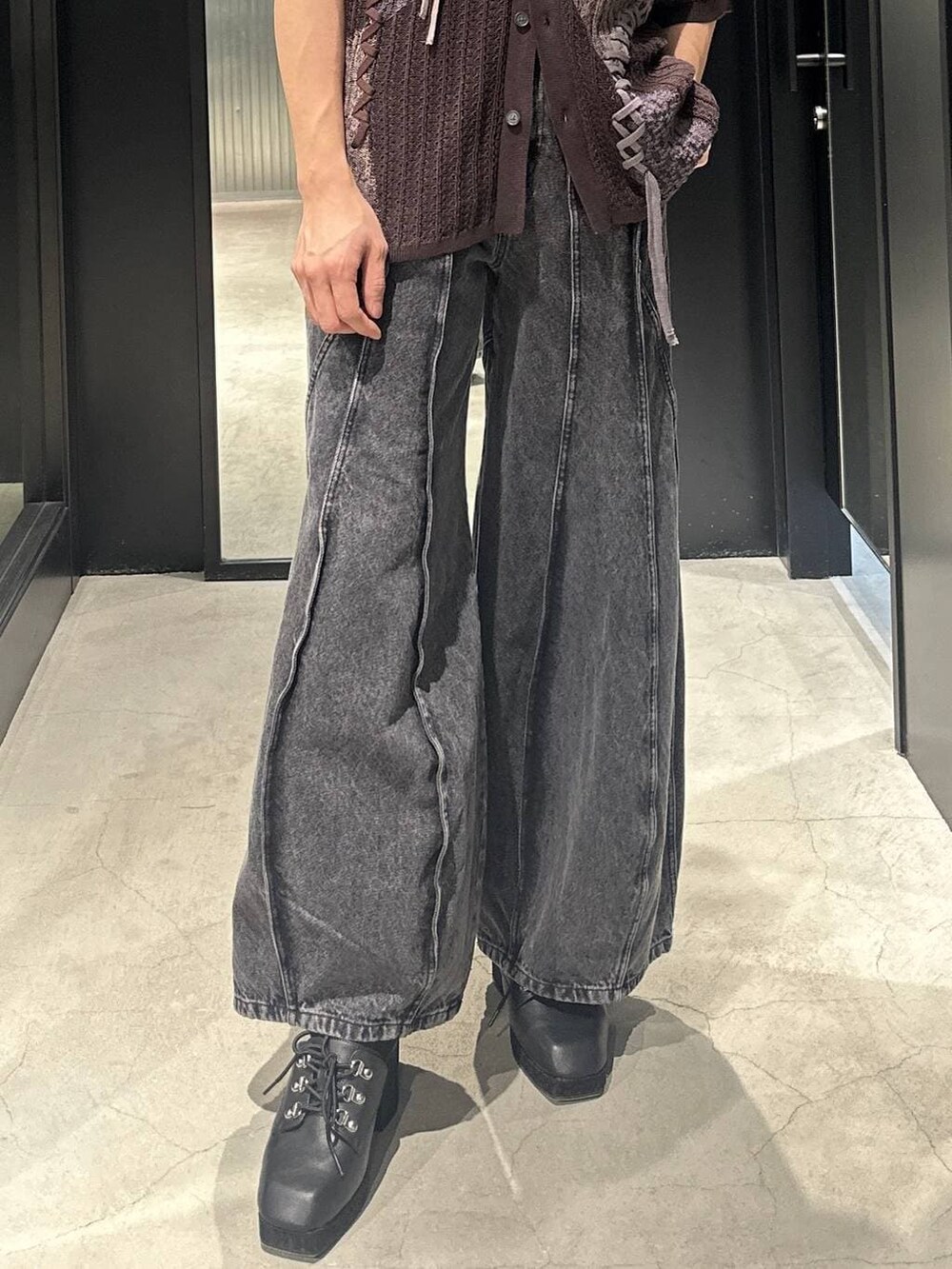 ブラック系のデニムパンツ、ブラック系のサンダル、ブラウン系のニット/セーターを着用したメンズの春コーディネートの3枚目の写真