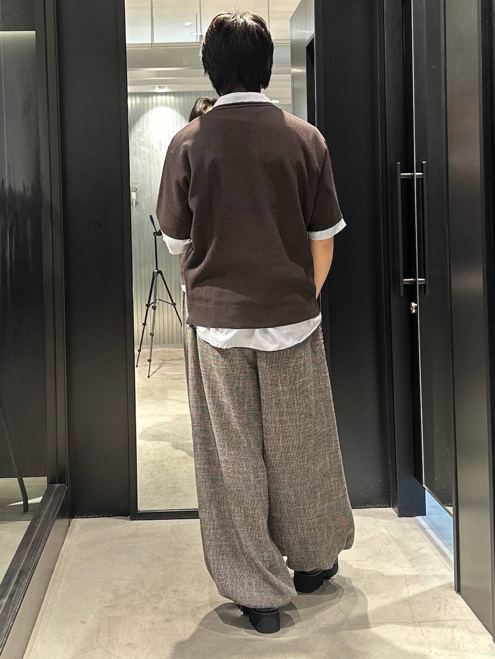 グレー系のスラックス、ブラック系のサンダル、ブラウン系のポロシャツを着用したメンズの春コーディネートの5枚目の写真