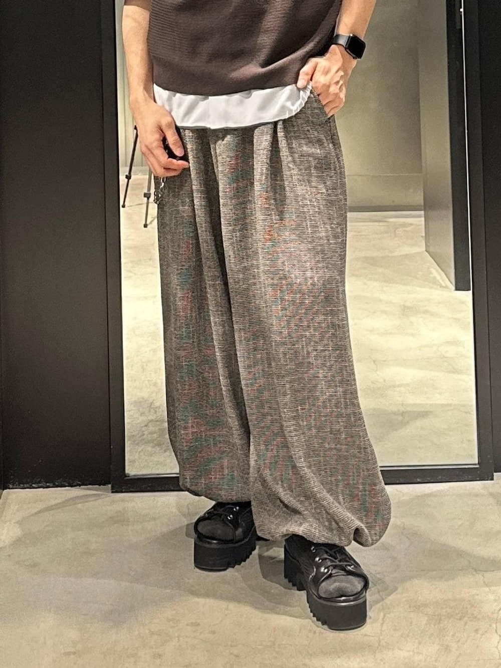 グレー系のスラックス、ブラック系のサンダル、ブラウン系のポロシャツを着用したメンズの春コーディネートの3枚目の写真