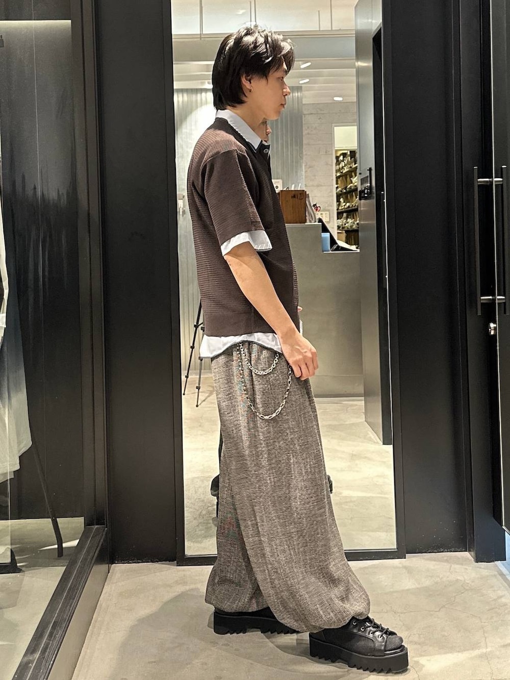 グレー系のスラックス、ブラック系のサンダル、ブラウン系のポロシャツを着用したメンズの春コーディネートの4枚目の写真