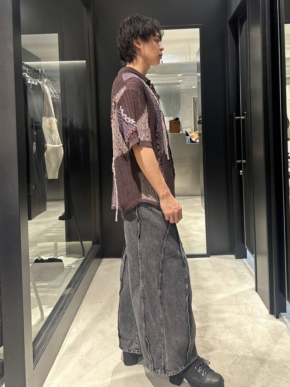 ブラック系のデニムパンツ、ブラック系のサンダル、ブラウン系のニット/セーターを着用したメンズの春コーディネートの4枚目の写真