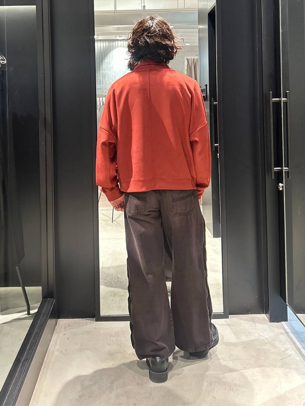 レッド系のデニムパンツ、オレンジ系のスウェットを着用したメンズの秋コーディネートの3枚目の写真