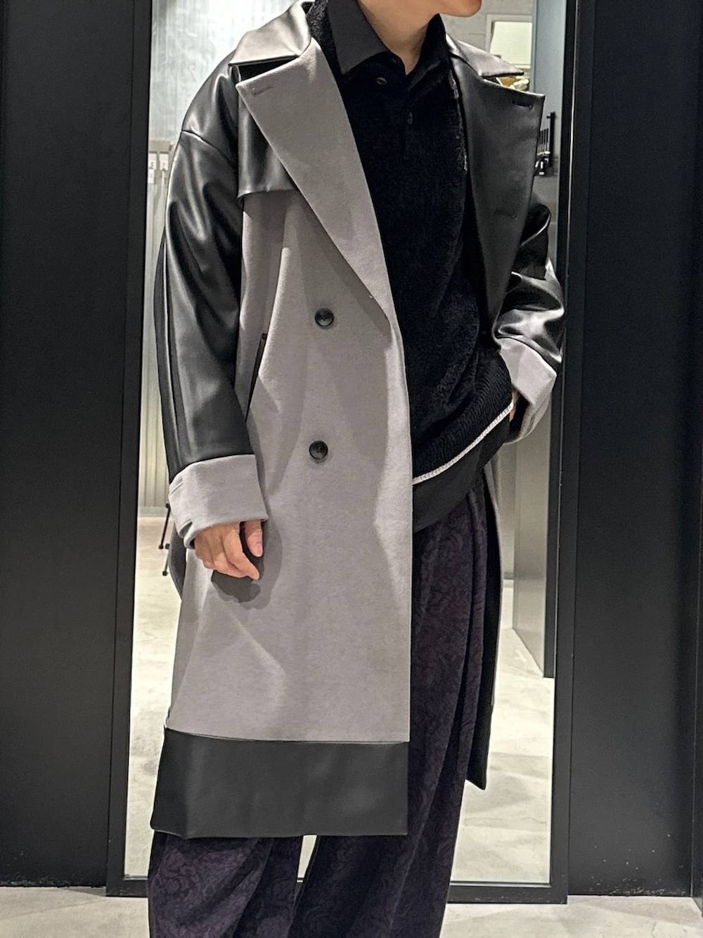 グレー系のトレンチコート、ブラック系のローファー、ブラック系のニット/セーターを着用したメンズの秋コーディネートの2枚目の写真