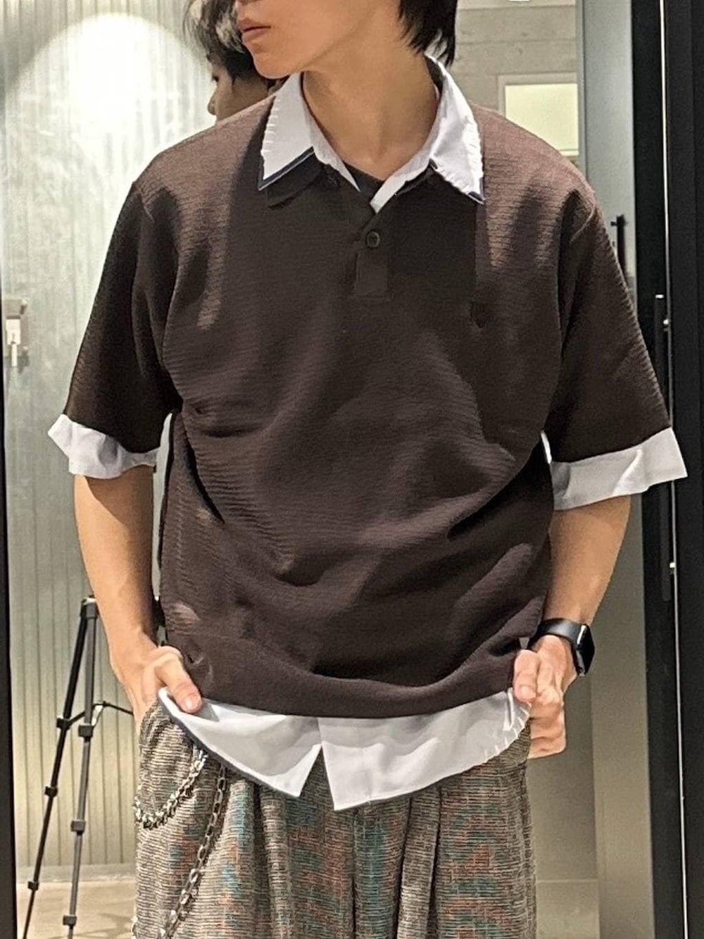 グレー系のスラックス、ブラック系のサンダル、ブラウン系のポロシャツを着用したメンズの春コーディネートの2枚目の写真