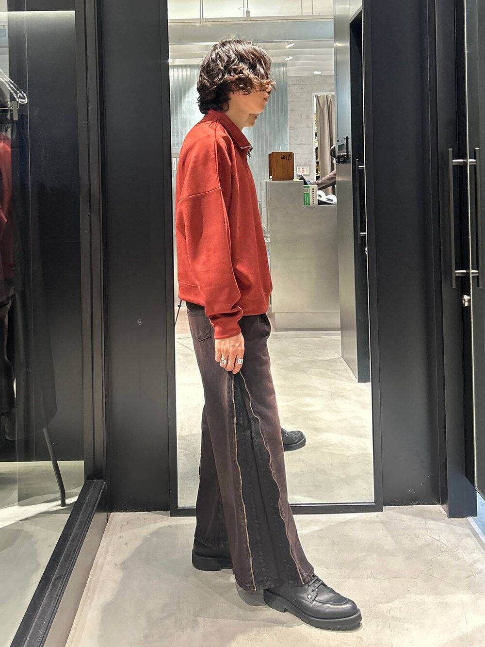 レッド系のデニムパンツ、オレンジ系のスウェットを着用したメンズの秋コーディネートの2枚目の写真